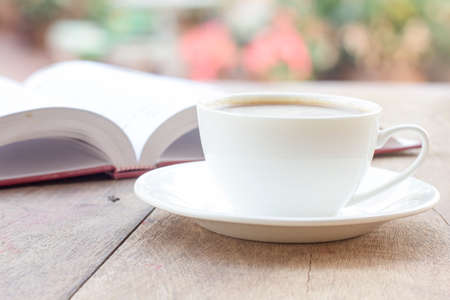 Cup of coffee and a book on a wooden tableの写真素材