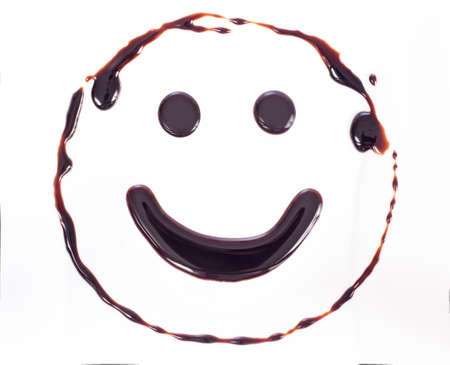 Smiley made of chocolate syrup is isolated on a whiteの写真素材