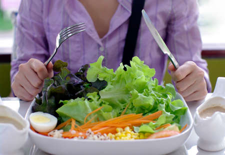girl with knife and fork eating saladの写真素材