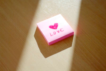 love and heart hand written message on post note in sun light
