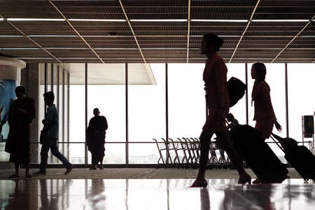 people silhouettes walking across terminal at airportの写真素材
