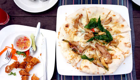 Italian Thai India fusion pizza style, pork with basil on nan pizza bread. And fired curry fish ballの写真素材