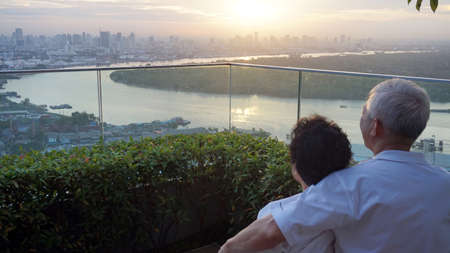 senior looking at sunrise together over city skyline and river