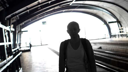 Silhouette for tourist girl backpacker waiting for train at the open station, travel abstract