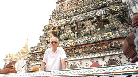Asian senior man traveling to wat pho, giants sculptures in the temple of Bangkok Thailandの写真素材