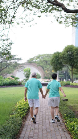 healthy asian senior couple exercise and walk together through the parkの写真素材