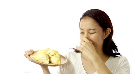 Asian girl smelling stinky durian. Smelly fruit in summer of tropical areaの写真素材