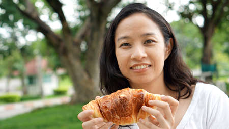 Asian woman mature adult eating bread carbohydratesの写真素材
