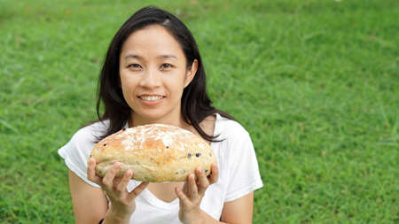 Asian woman mature adult eating bread carbohydratesの写真素材