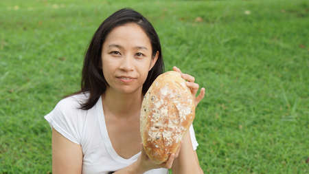 Asian woman mature adult eating bread carbohydratesの写真素材