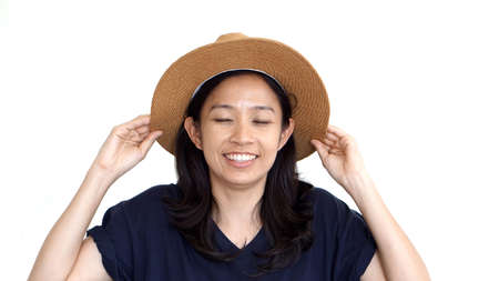 Casual friendly asian girl wearing hat relaxing and smiling on white backgroundの写真素材
