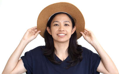 Casual friendly asian girl wearing hat relaxing and smiling on white backgroundの写真素材