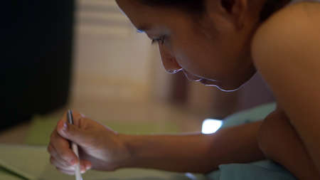 Asian girl playing smartphone at night in low light house. Bad for eye sightの写真素材