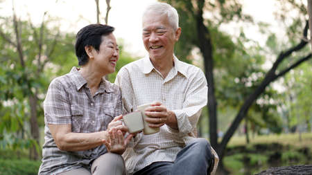 Start day with morning coffee, Asian senior retired couple sitting in green copy spaceの写真素材