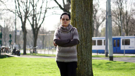 Asian senior woman travel in europe taking potrait in parkの写真素材