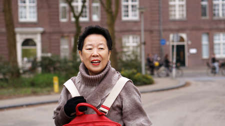 Asian senior woman smiling and having fun in her Europe travel tripの写真素材