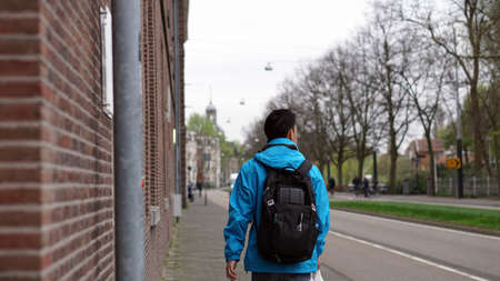 Asian backpacker man walk alone in European city streetの写真素材