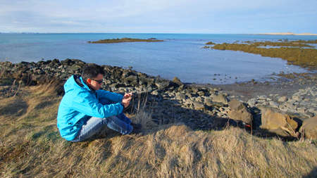 Asian man using smart phone for internet gps in remote nature area of Icelandの写真素材