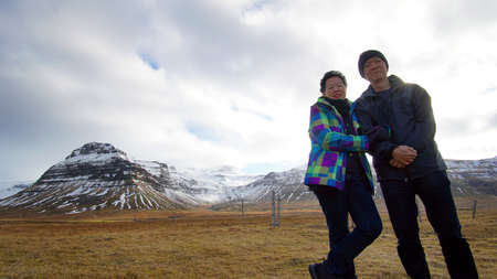 Asian senior couple enjoy anniversary trip in Europe. Iceland volcanic landscape mountain with snow viewの写真素材
