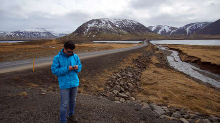 Asian man using smart phone for internet gps for road trip and social media during journey in Icelandの写真素材
