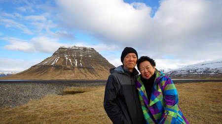 Asian senior on road trip in Europe, Iceland. photo at landmark Kirkjufell mountainの写真素材