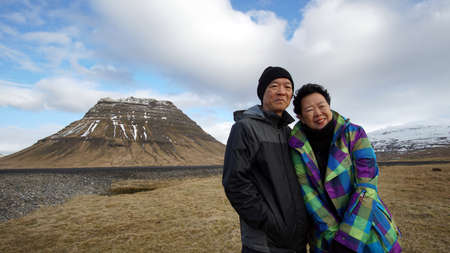 Asian senior on road trip in Europe, Iceland. photo at landmark Kirkjufell mountain from side viewの写真素材