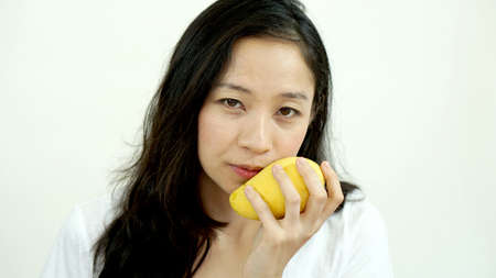 Asian beautiful woman eating mango. Summer delight tropical fruit.の写真素材