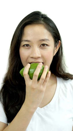 Asian girl eating fruit, avocado. Clean food for health and weight conceptの写真素材