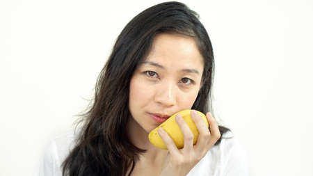 Asian beautiful woman eating posing with mango. Summer delight tropical fruit.の写真素材