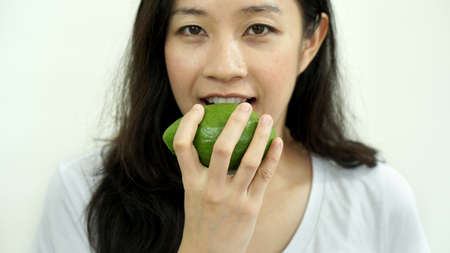 Asian girl eating fruit, avocado. Clean food for health and weight conceptの写真素材