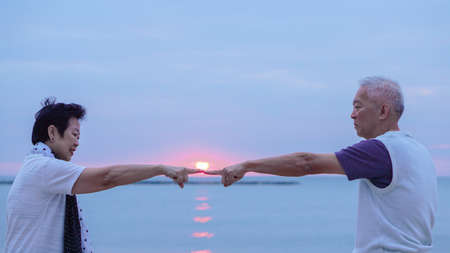 Asian senior couple together at sunrise beach. New year, new chapter conceptの写真素材