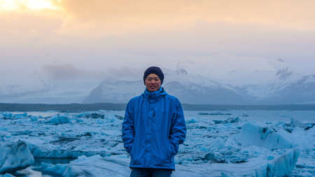 Asian man stand in front of million years old iceberg at glacier lagoon Icelandの写真素材