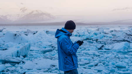 Asian man using smart phone at jokulsarlon, Glacier lagoon Iceland.  World travel destinationの写真素材