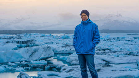 Asian man stand in front of million years old iceberg at glacier lagoon Icelandの写真素材