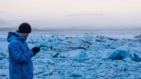 Asian man using smart phone at jokulsarlon, Glacier lagoon Iceland.  World travel destinationの写真素材