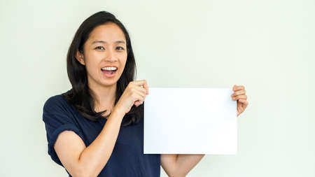 Casual beautiful Asian woman holding white sign with copy spaceの写真素材