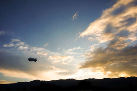 Helium blimp advertising ballon floating sunset sky and mountain backgroundの写真素材