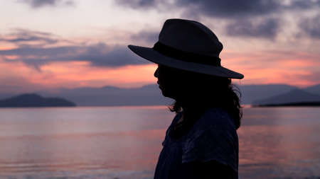 Asian woman silhouette at sunrise ocean pink and orange skyの写真素材
