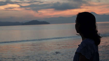 Asian woman silhouette at sunrise ocean pink and orange skyの写真素材