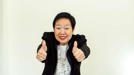 Asian senior woman wearing suit with happpy face and hand gestureの写真素材