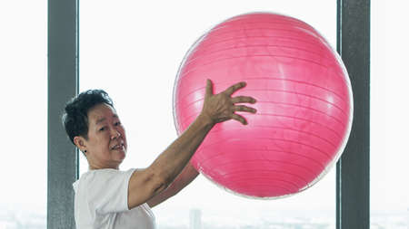 Asian senior old healthy woman exercise with pink yoga ballの写真素材