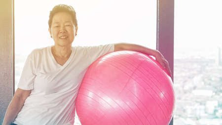 Asian senior old healthy woman exercise with pink yoga ballの写真素材