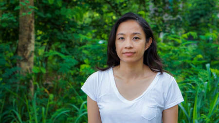Asian woman long hair facial epression green nature backgroundの写真素材