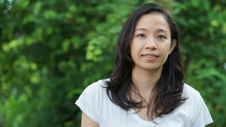 Asian woman long hair facial epression green nature backgroundの写真素材