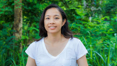 Asian woman long hair facial epression green nature backgroundの写真素材