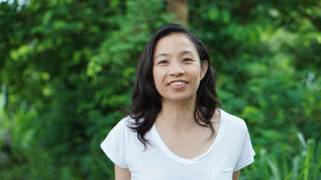 Asian woman long hair facial epression green nature backgroundの写真素材