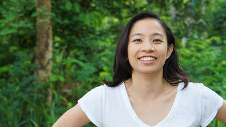 Asian woman long hair facial epression green nature backgroundの写真素材
