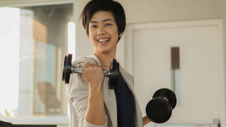 Smiling Asian short hair woman fitness dumbbell lifting. Healthy exerciseの写真素材