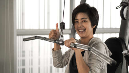 Asian woman fitness training machine smile faceの写真素材