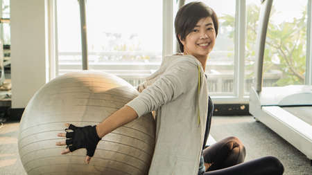 Asian woman short hair in sport fitness with yoga ball, healthy lifestyleの写真素材